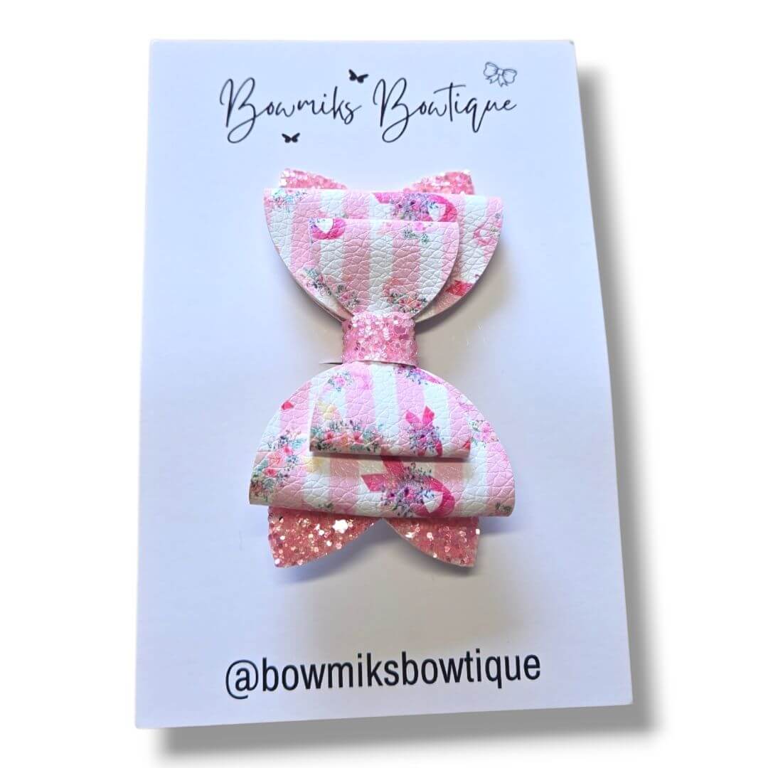 Boutique hair accessories for kids featuring a stylish pink bow with floral patterns and glitter accents.