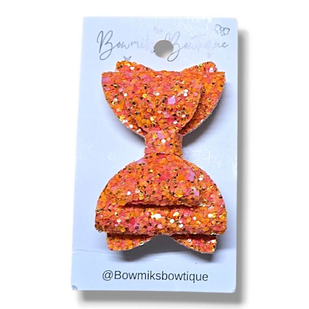 Bowmiks Boutique Hair accessories, a vibrant pink glitter bow clip on a card packaging.