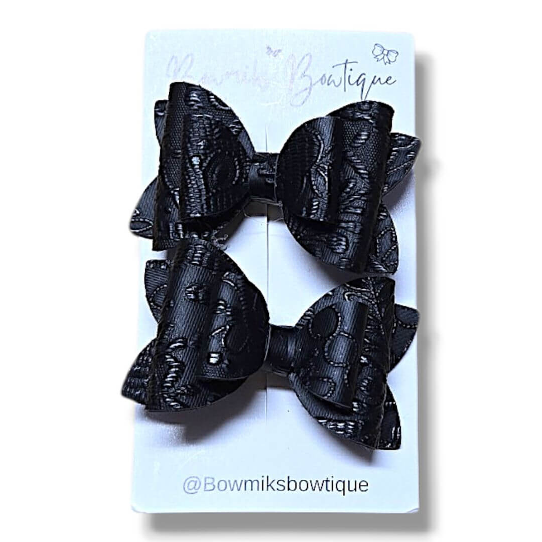 Handmade boutique hair accessories featuring a pair of elegant black bow clips on a display card.