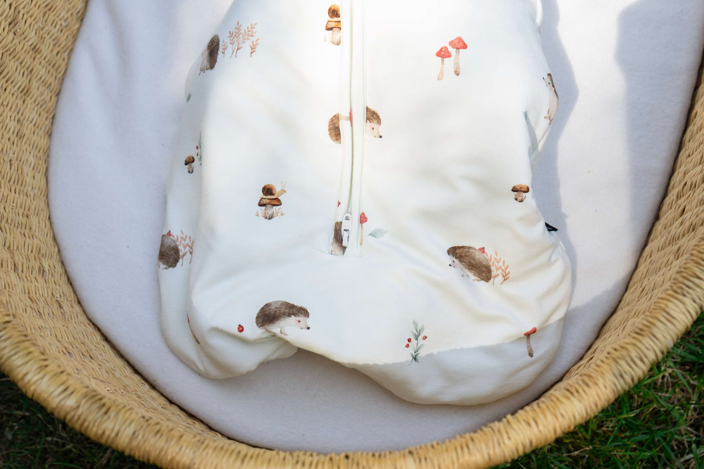 Convertible swaddle sack for babies featuring hedgehogs and mushrooms design in a woven basket.