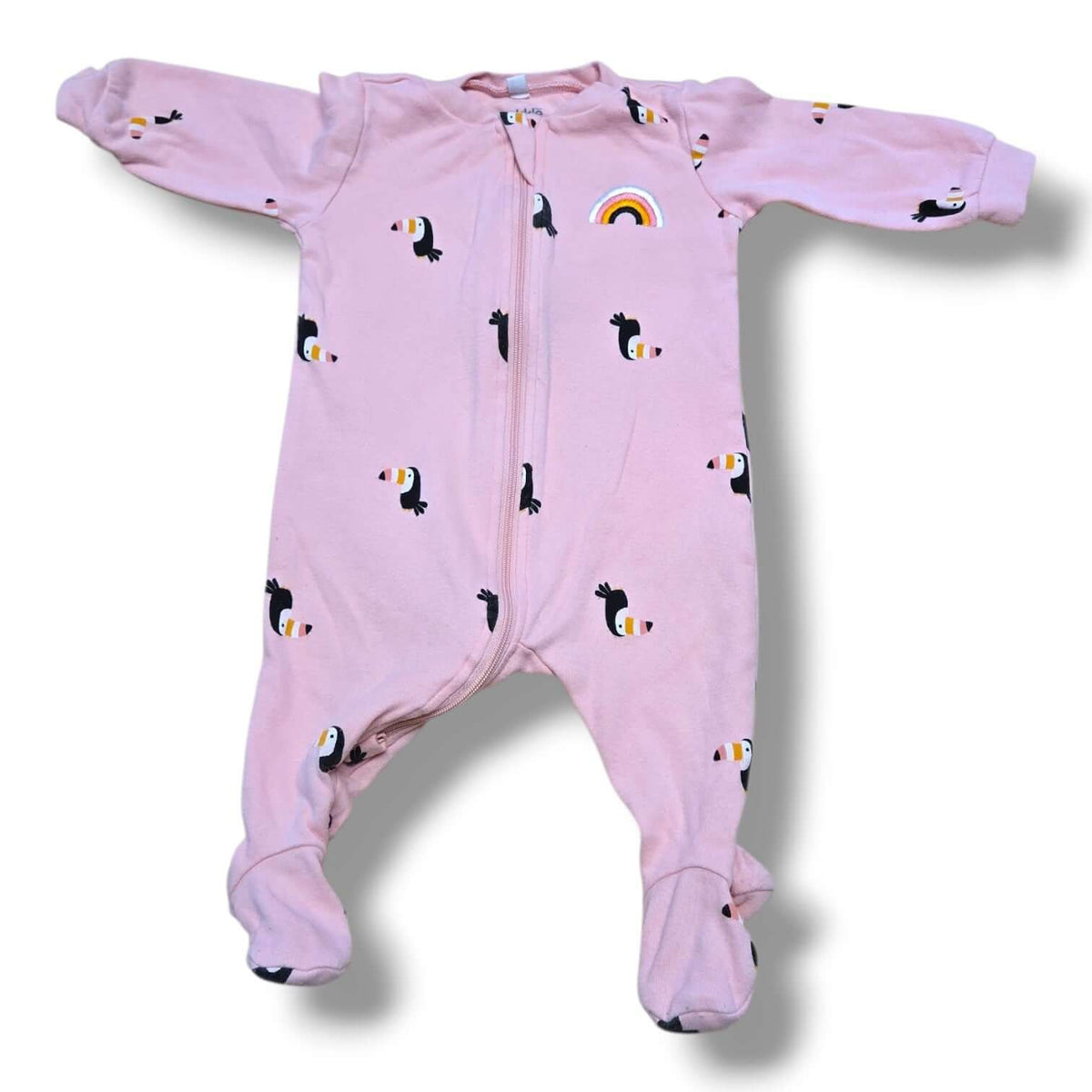 Pekkle pre-loved baby sleeper in size 3 months with toucan print and rainbow detail on pink background.