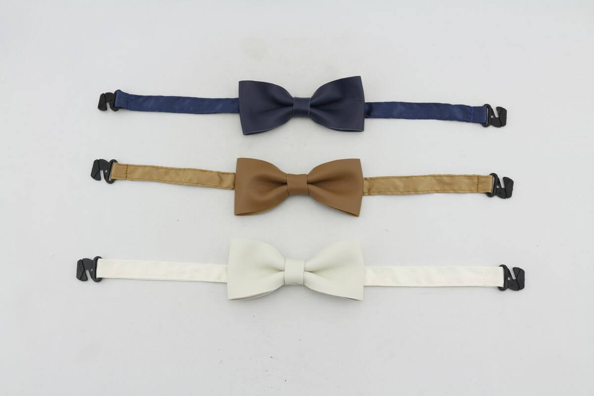 Three baby leather bow ties in navy, tan, and white with adjustable straps for a perfect fit.