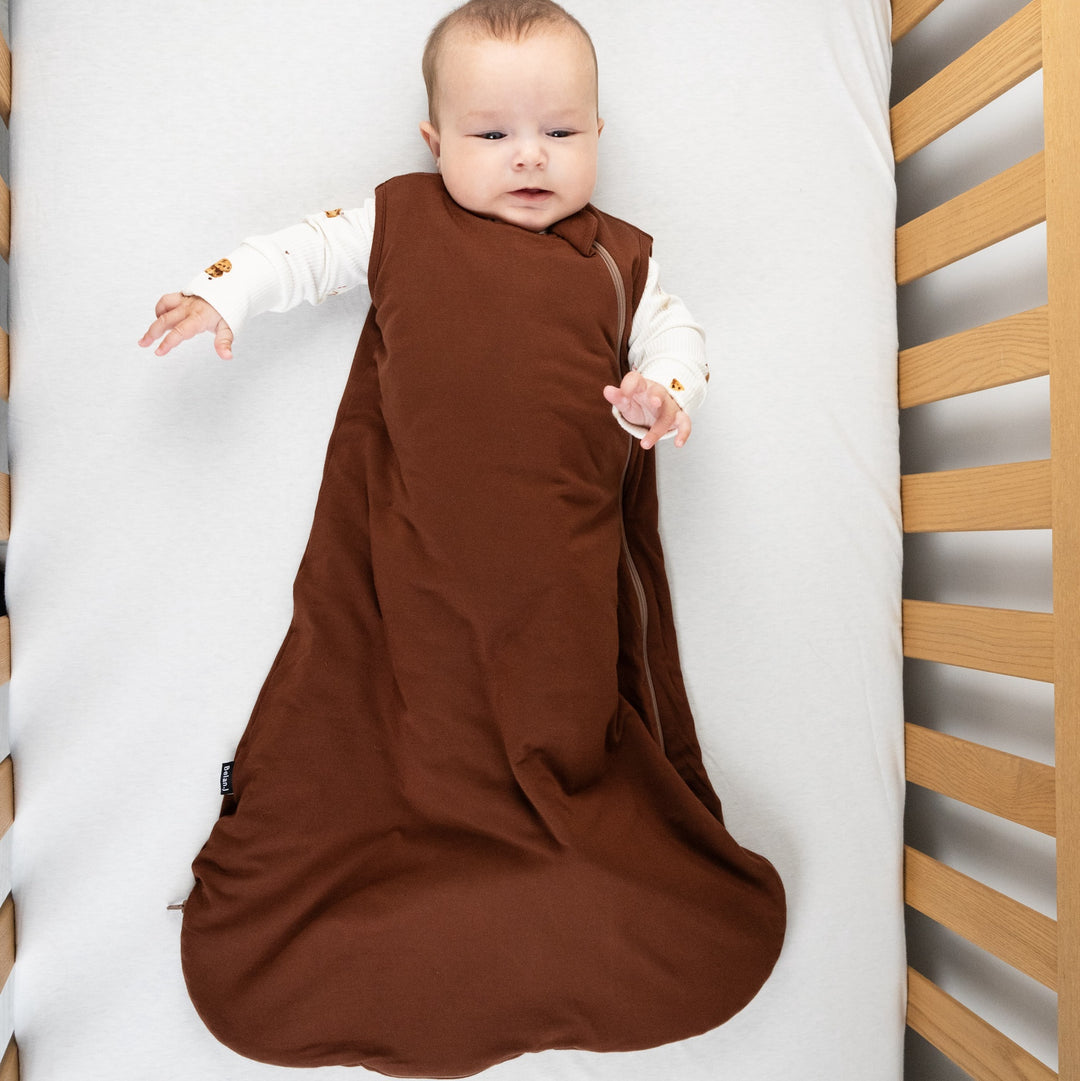 Baby wearing a cocoa bamboo sleep sack for babies, designed for comfort and movement in a crib.