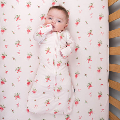 1.0 TOG convertible swaddle sack in pink bows design with baby in a crib.