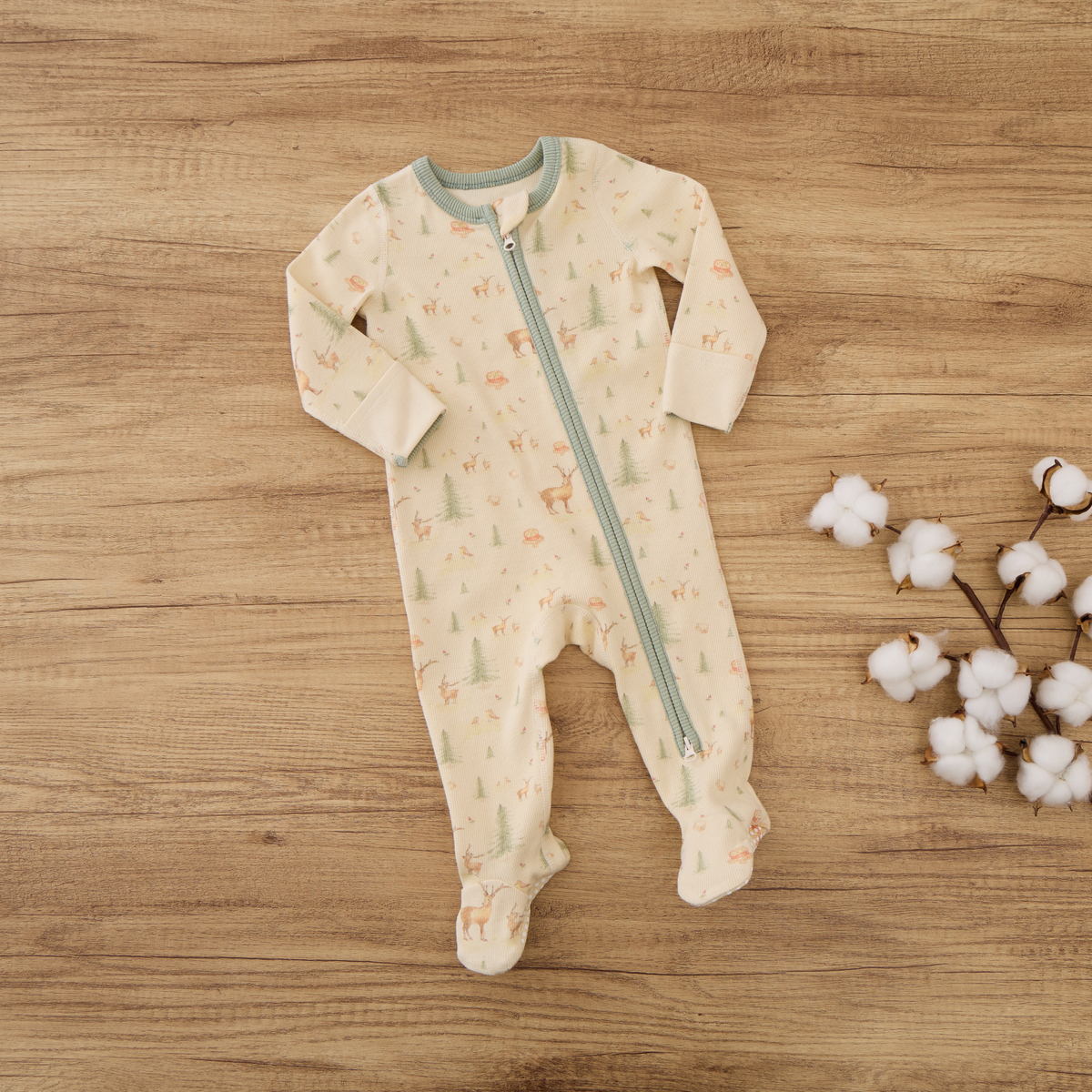 Blara Organic House long-sleeve ribbed organic cotton footie romper with zipper and footies on wooden background.