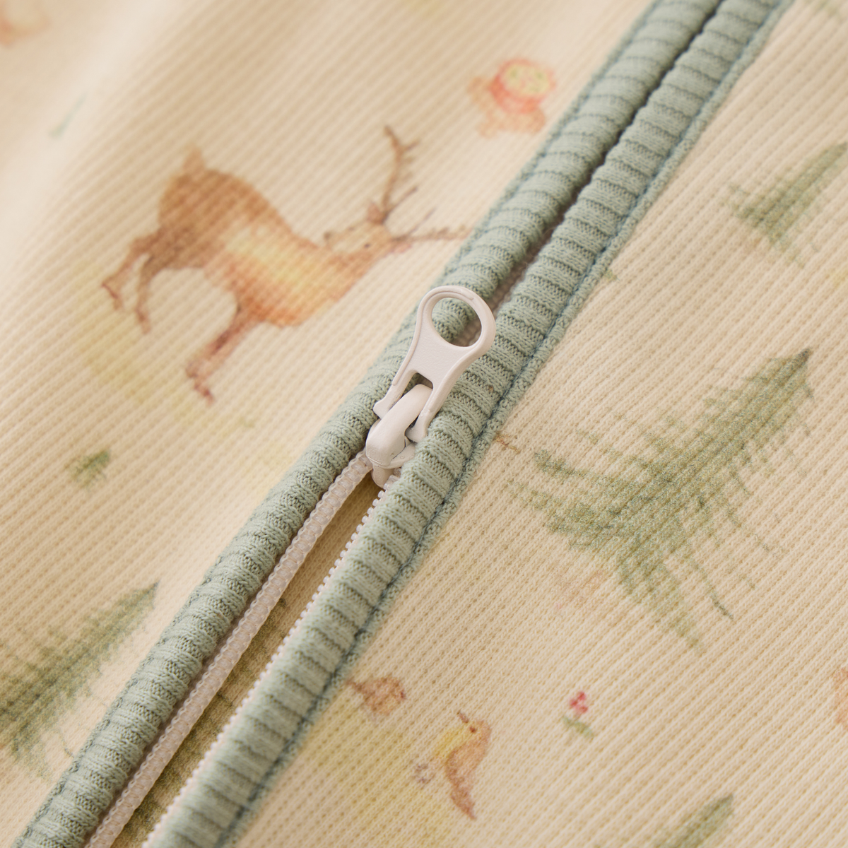 Close-up of the zipper detail on Blara Organic House's organic cotton footie romper with vibrant animal prints.