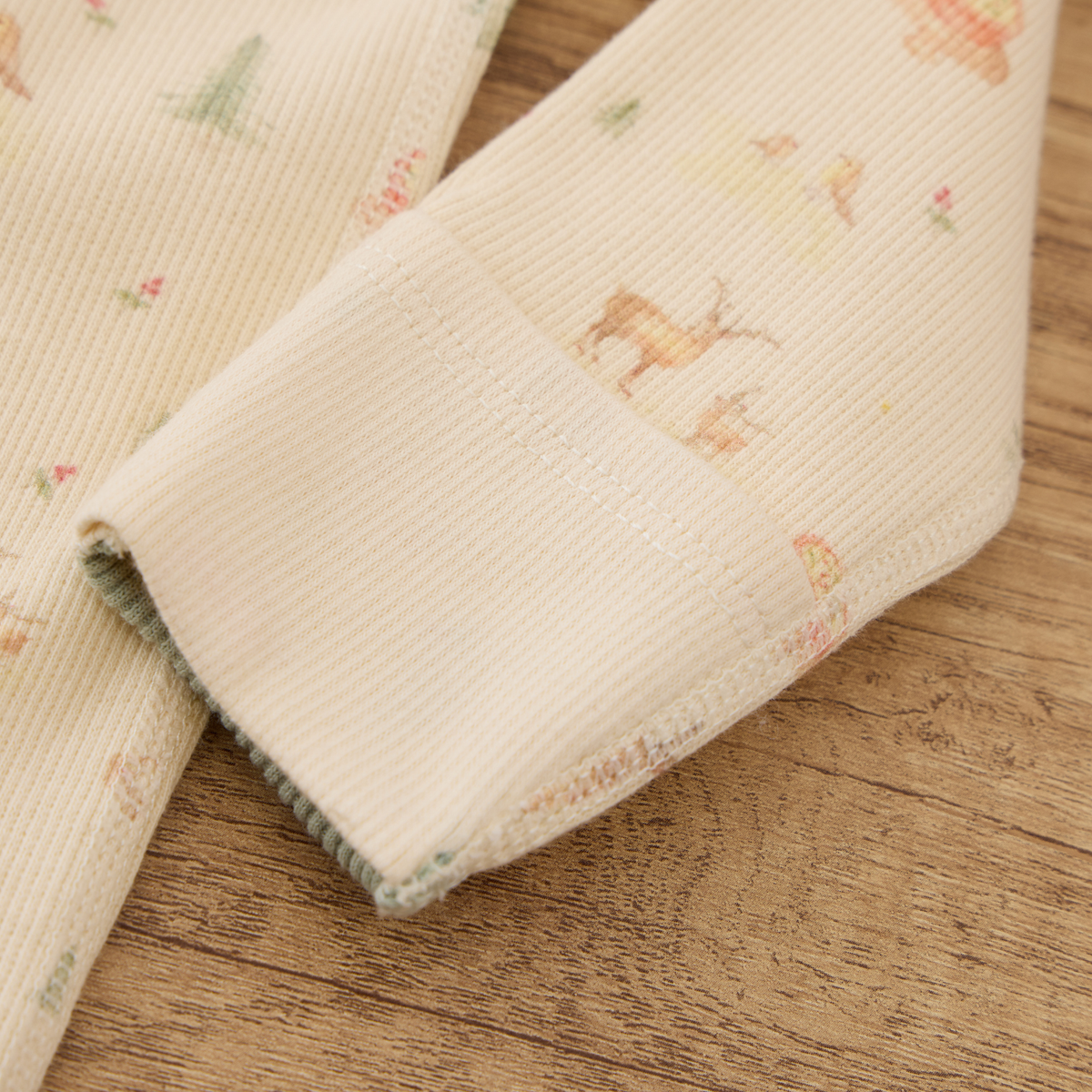 Detail of the sleeve cuff of Blara Organic House organic cotton footie romper featuring soft ribbed fabric.
