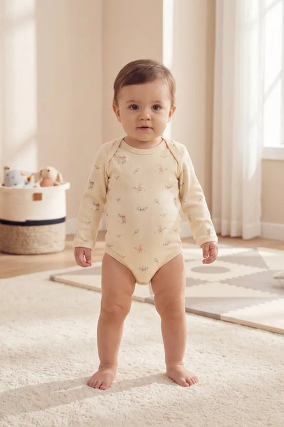 Baby wearing an organic cotton bodysuit from the organic cotton baby gift set, standing in a bright, cozy room.