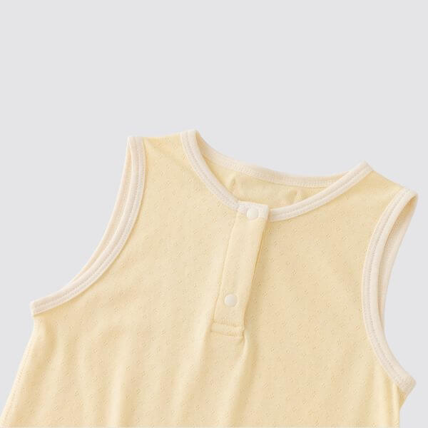 organic cotton sleeveless baby bodysuit in creamy yellow with a button closure and soft fabric.