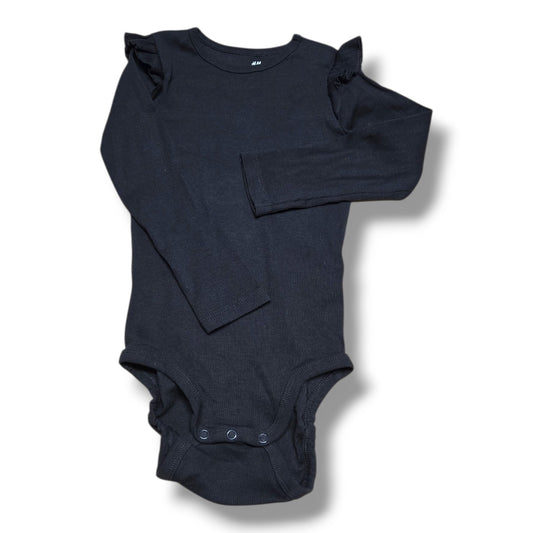 Pre-loved onesie H&M in black with long sleeves and ruffle details, showing normal signs of wear.